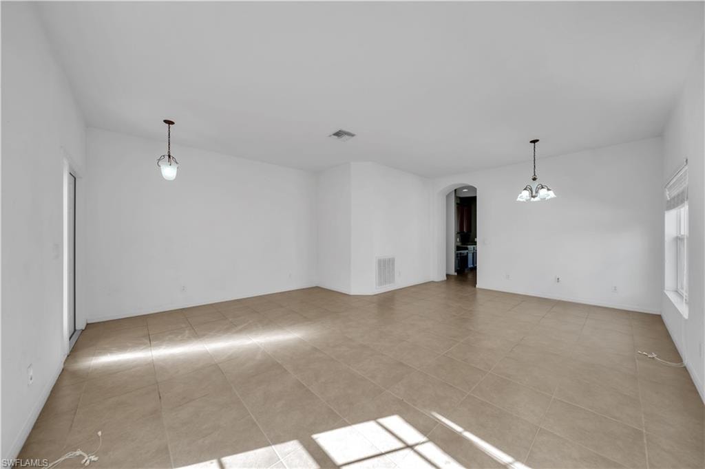 Unfurnished room featuring arched walkways and a chandelier