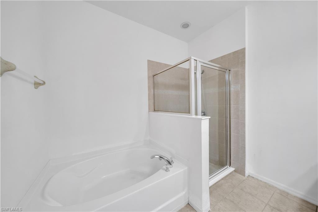 Bathroom featuring a garden tub, a stall shower, and light tile patterned floors