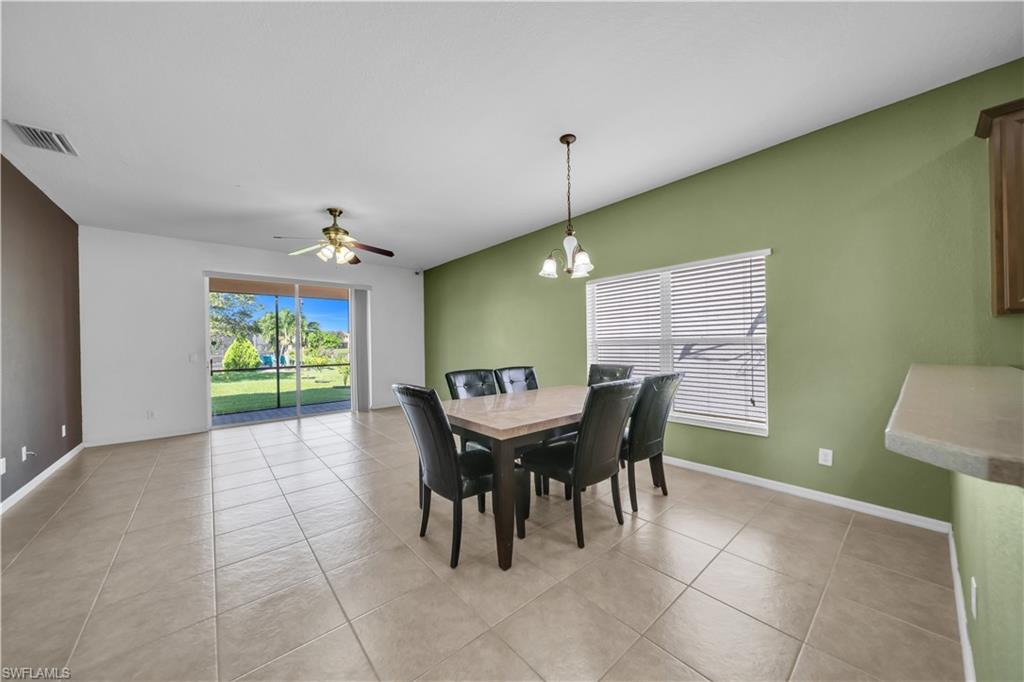Dining space with a ceiling fan, light tile patterned flooring, and a chandelier
