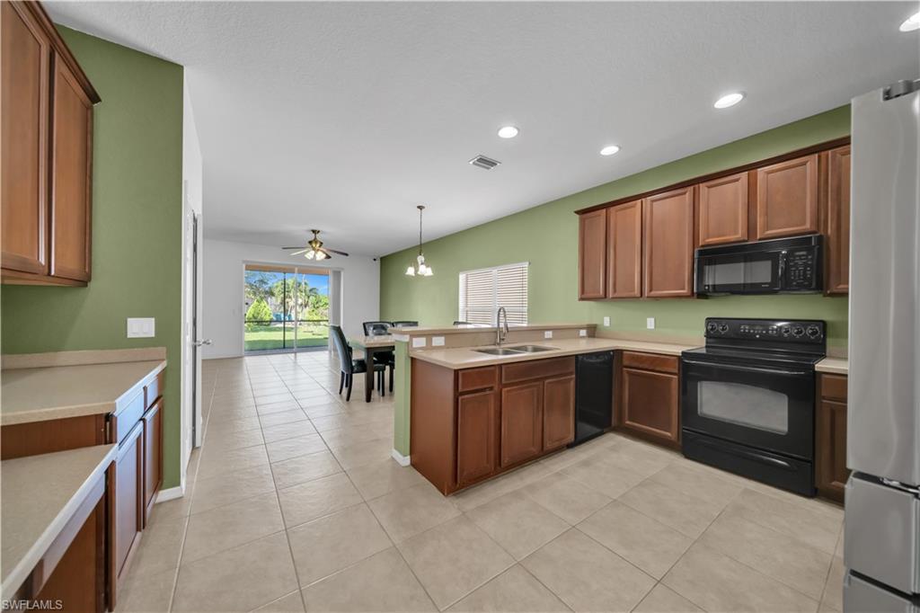 Kitchen with black appliances, light countertops, recessed lighting, a peninsula, and pendant lighting