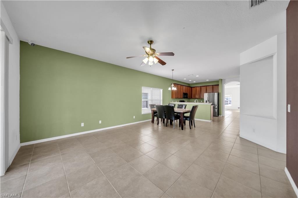 Dining room featuring arched walkways, ceiling fan, and light tile patterned floors