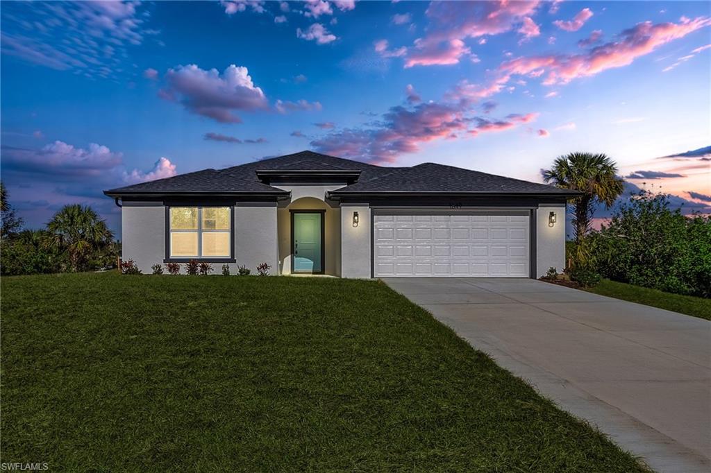 View of front of property featuring a lawn and a garage