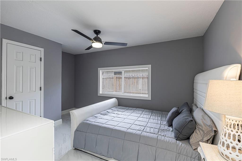 Bedroom with ceiling fan and light marble finish floors
