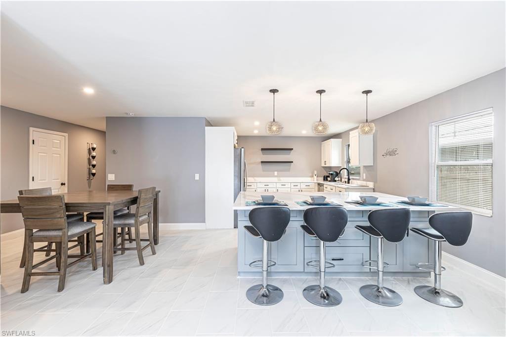 Kitchen featuring white cabinetry, a breakfast bar area, open shelves, a peninsula, and decorative light fixtures