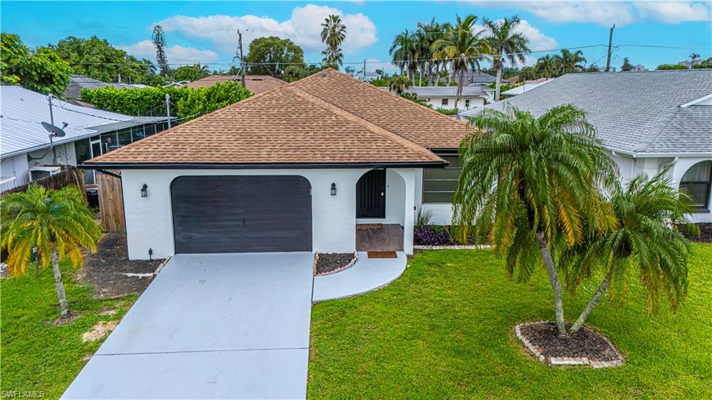 Single story home with stucco siding, roof with shingles, driveway, and a garage