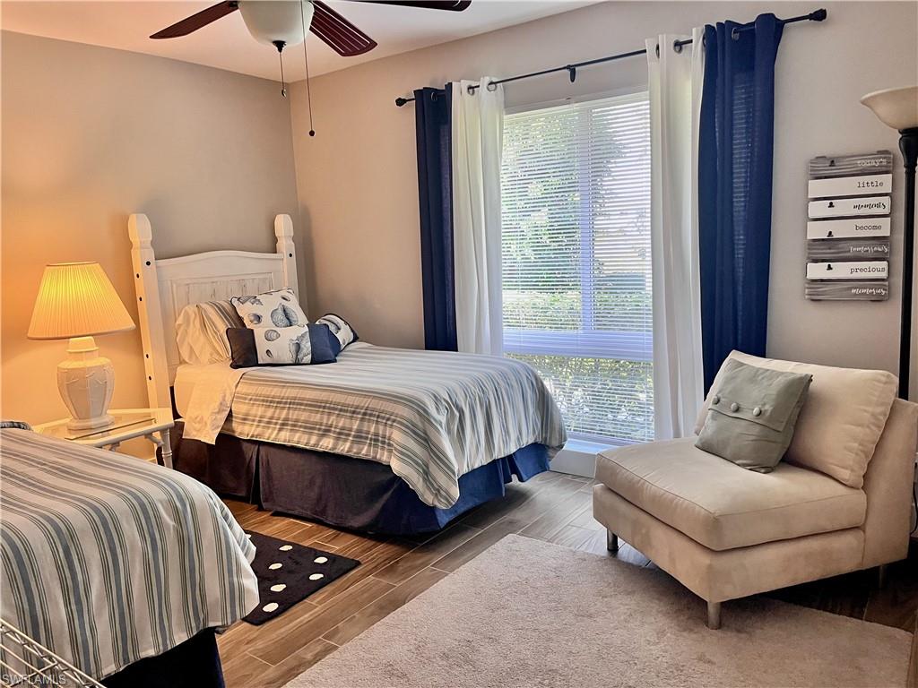 Bedroom with wood finished floors and ceiling fan with large closet, TV and chair
