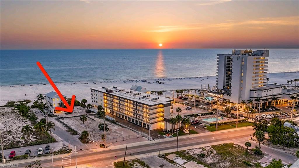 Aerial view at dusk of view of water and beach and a view of apartment building / complex