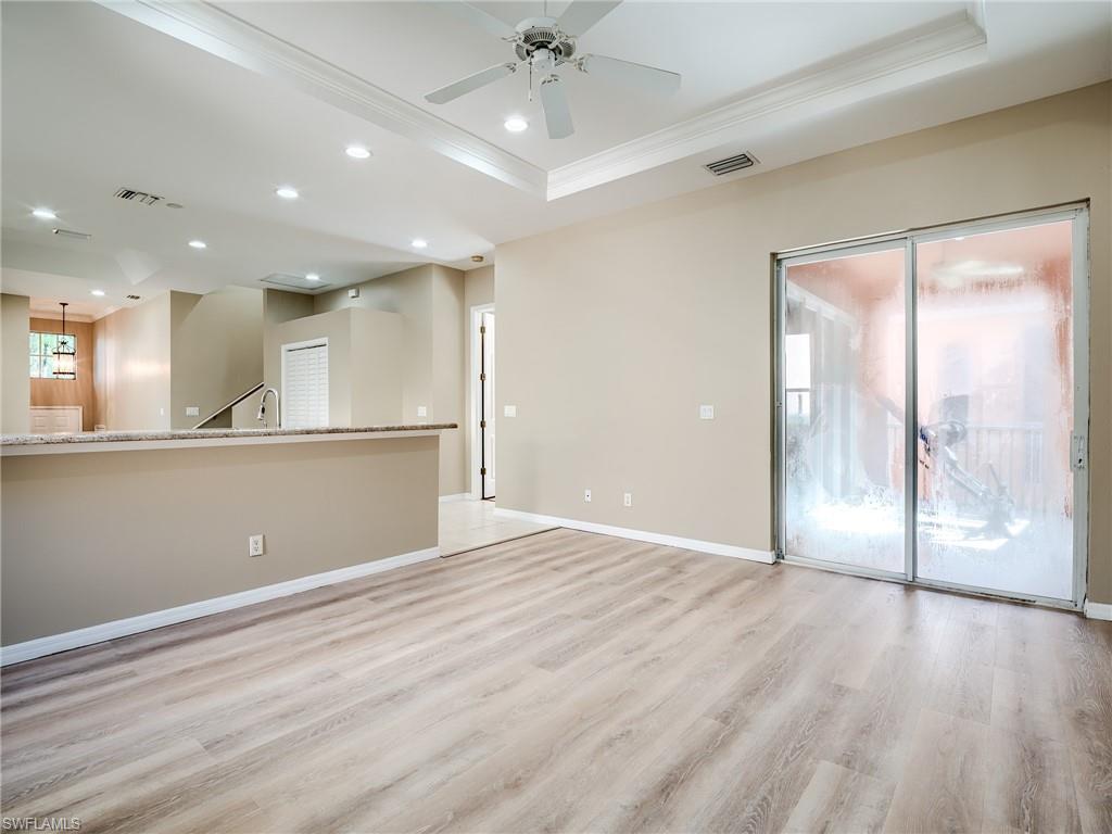 Empty room featuring light wood finished floors, recessed lighting, ceiling fan, a tray ceiling, and crown molding