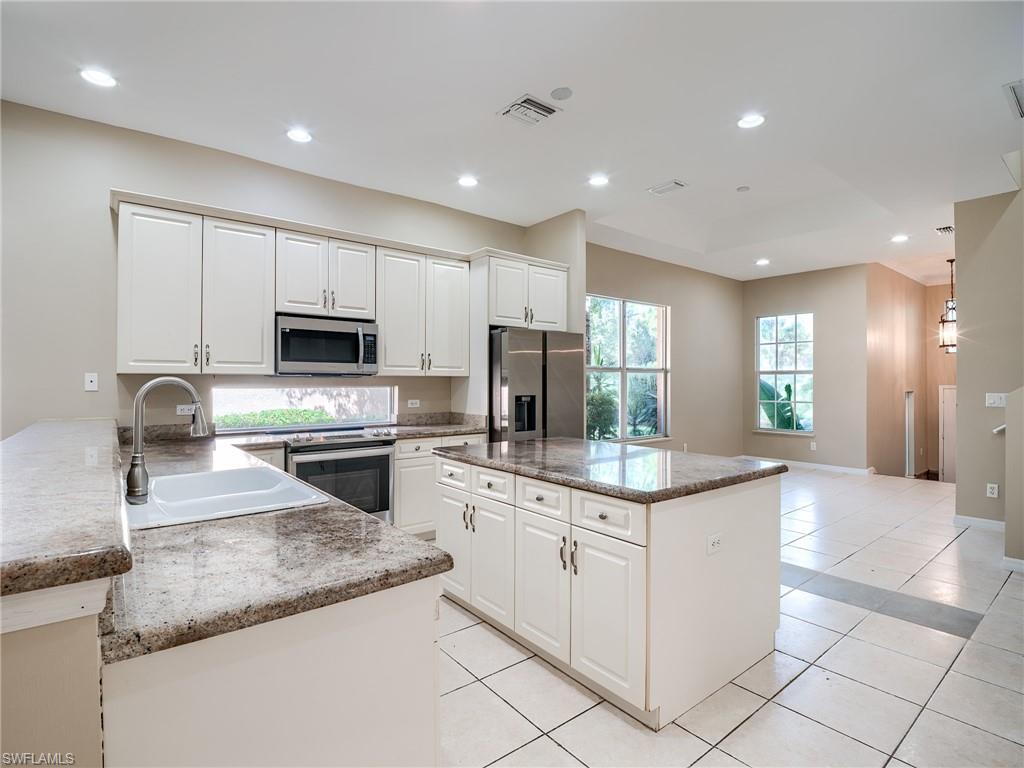 Kitchen with recessed lighting, appliances with stainless steel finishes, white cabinets, a kitchen island, and light tile patterned flooring