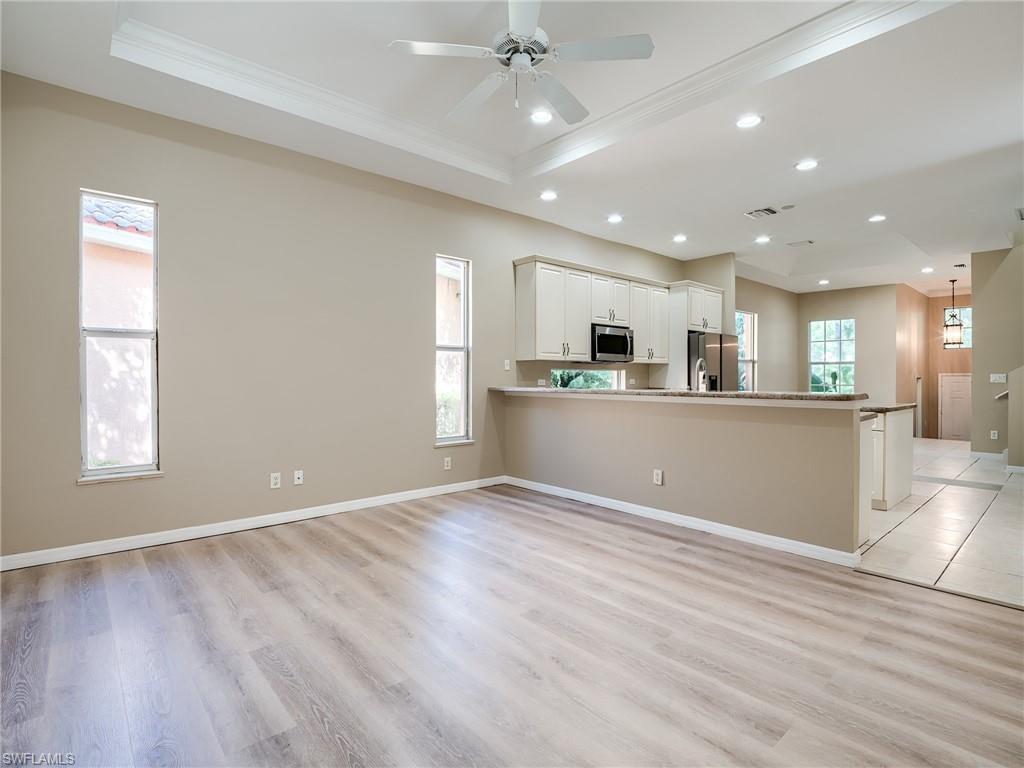 Kitchen with white cabinets, a peninsula, a tray ceiling, open floor plan, and recessed lighting