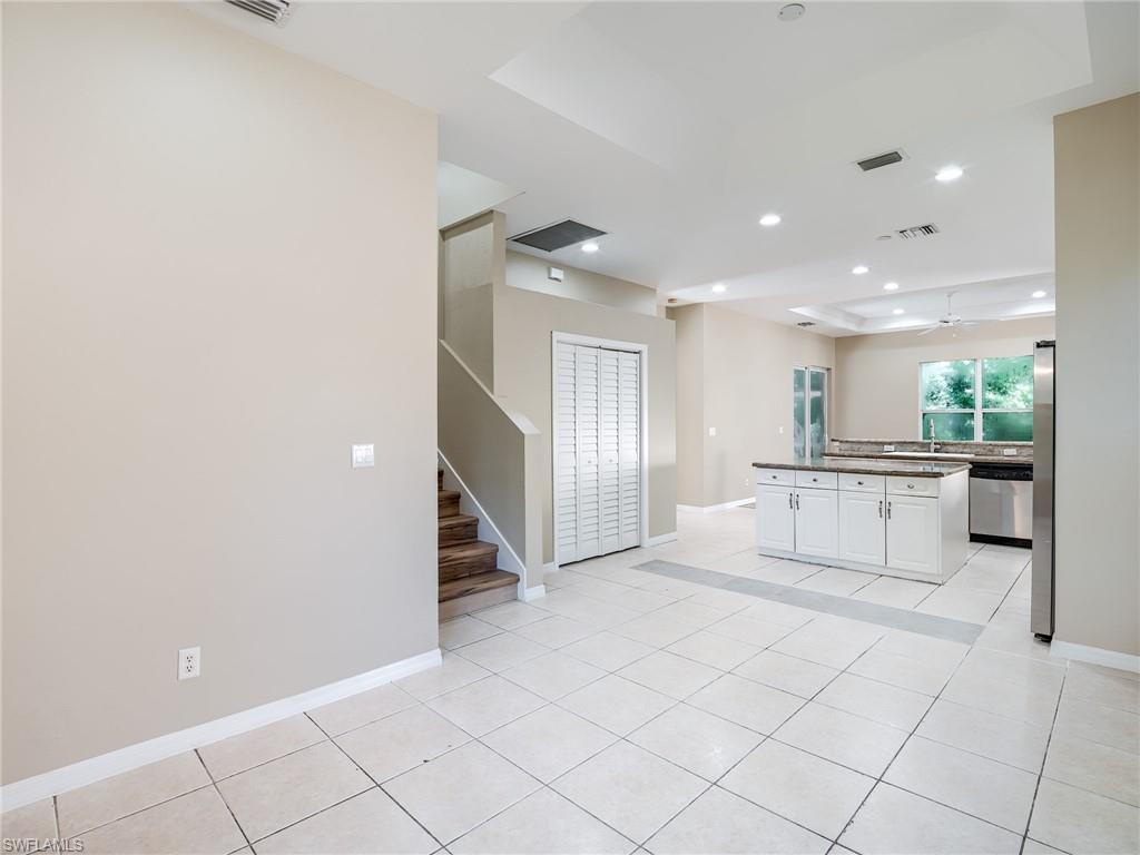 Kitchen with a raised ceiling, recessed lighting, white cabinetry, a kitchen island, and stainless steel appliances
