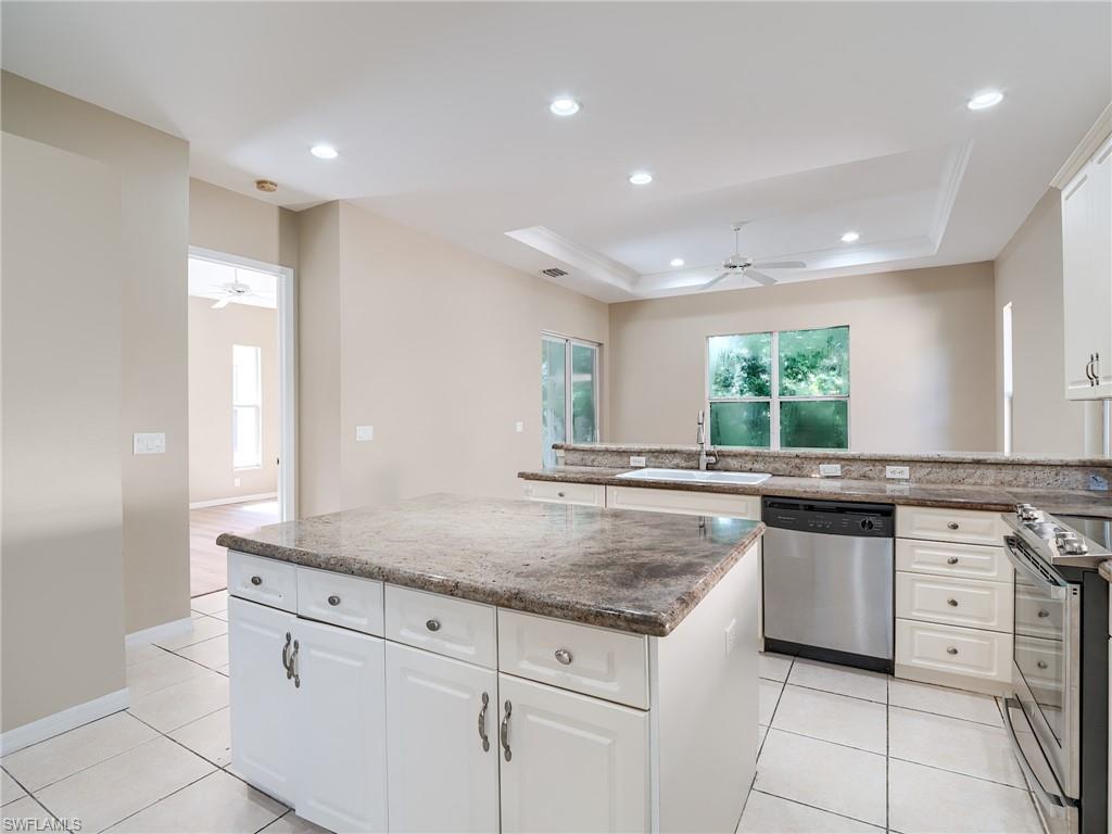 Kitchen featuring ceiling fan, stainless steel appliances, a tray ceiling, recessed lighting, and ornamental molding