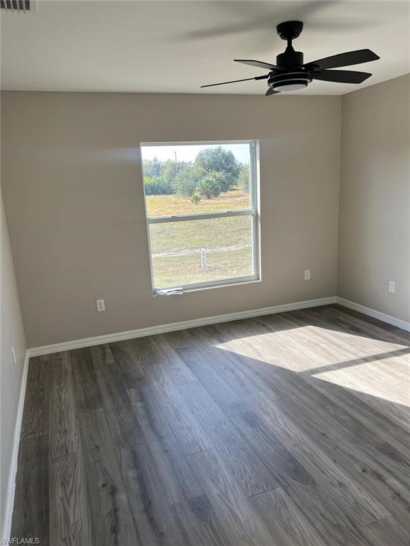 Spare room featuring a ceiling fan and dark wood-style flooring