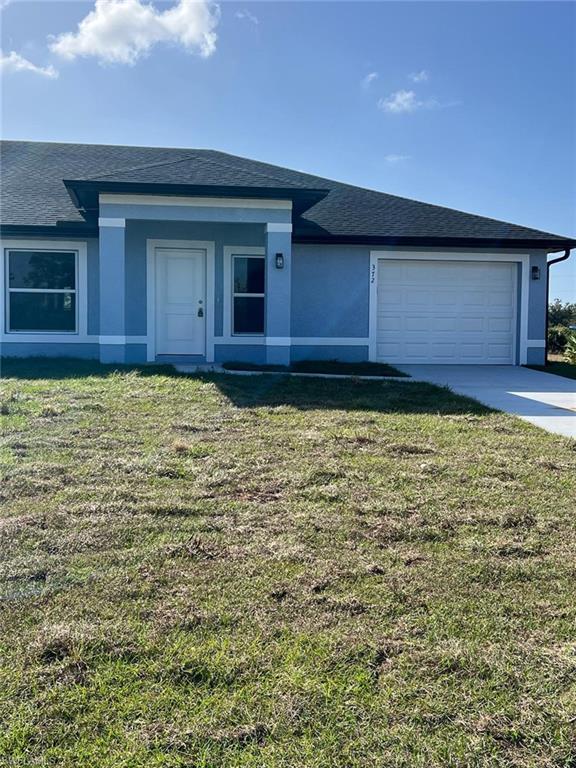 View of front of house featuring a shingled roof, a front yard, stucco siding, and an attached garage