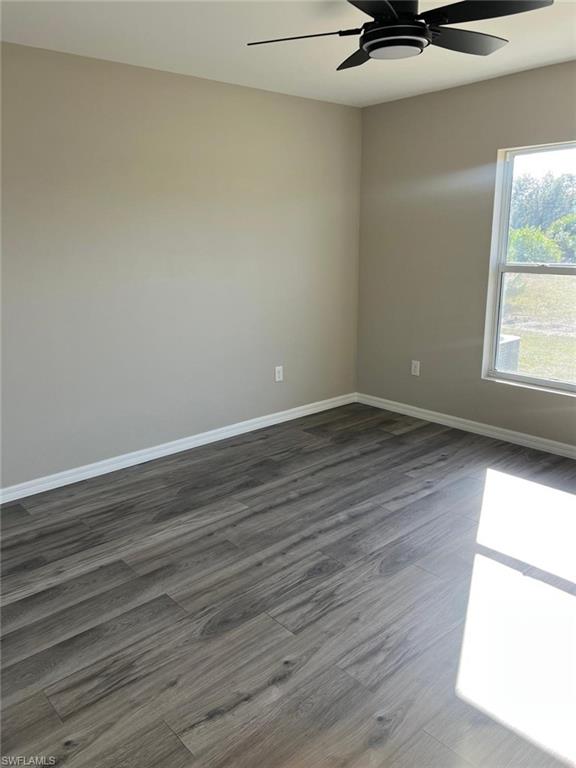 Spare room featuring dark wood-style floors and a ceiling fan