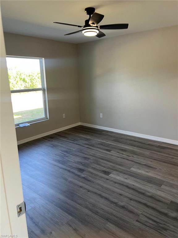 Unfurnished room with dark wood-type flooring and ceiling fan