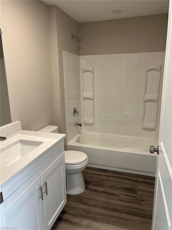 Bathroom featuring vanity, dark wood-style floors, and shower / tub combination