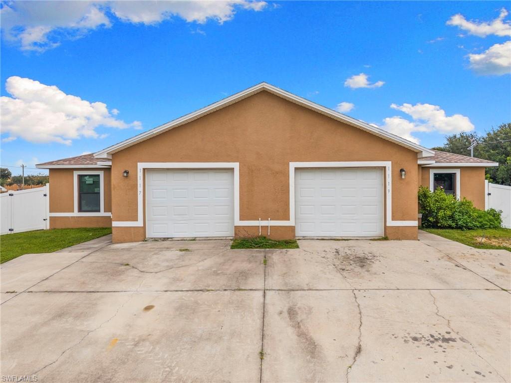 View of front of home featuring stucco siding, driveway, a gate, and a garage
