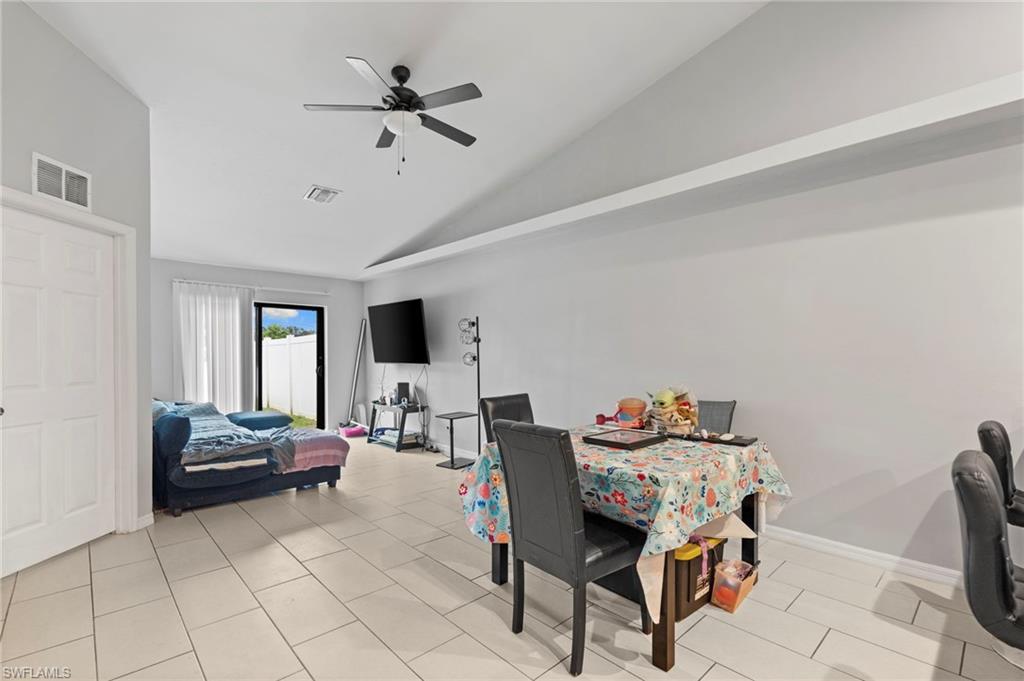 Dining space with lofted ceiling, a ceiling fan, and light tile patterned flooring