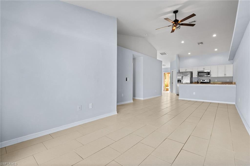 Unfurnished living room featuring vaulted ceiling, recessed lighting, a ceiling fan, and light tile patterned floors