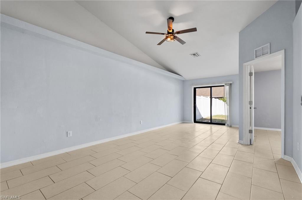 Unfurnished room featuring lofted ceiling, a ceiling fan, and light tile patterned flooring