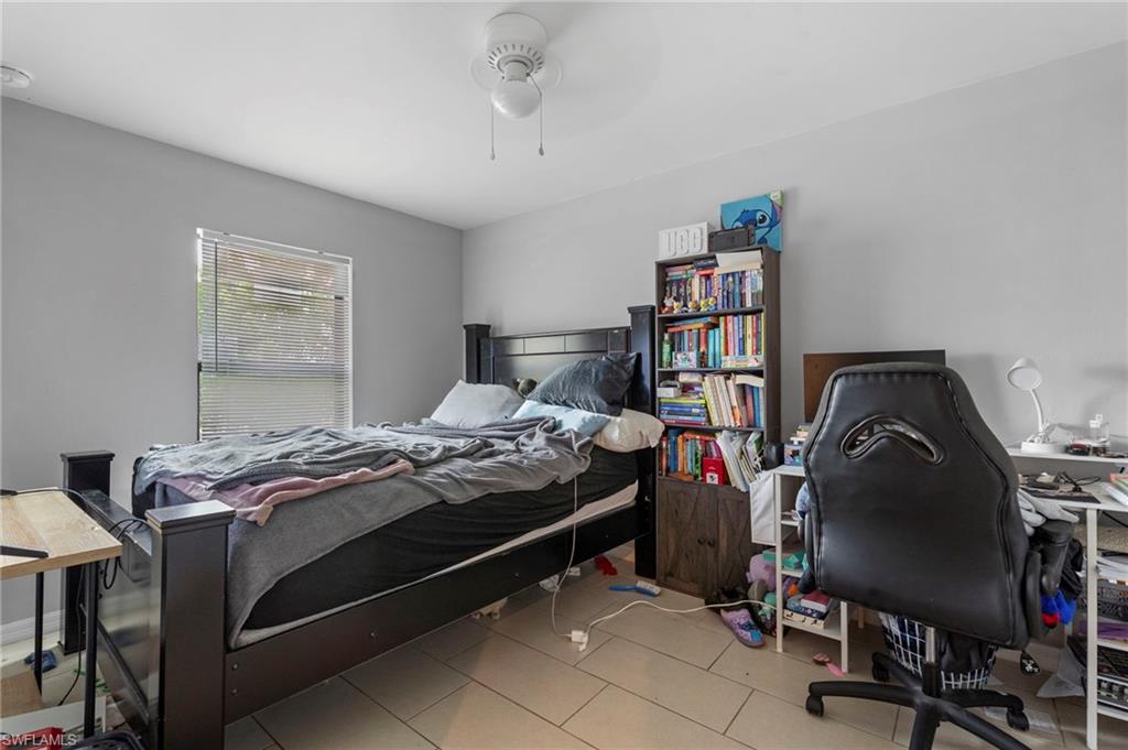 Bedroom featuring a desk, ceiling fan, and light tile patterned floors