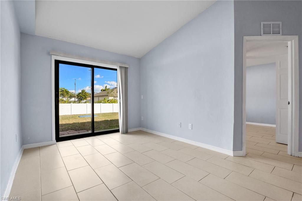 Empty room featuring vaulted ceiling and light tile patterned floors