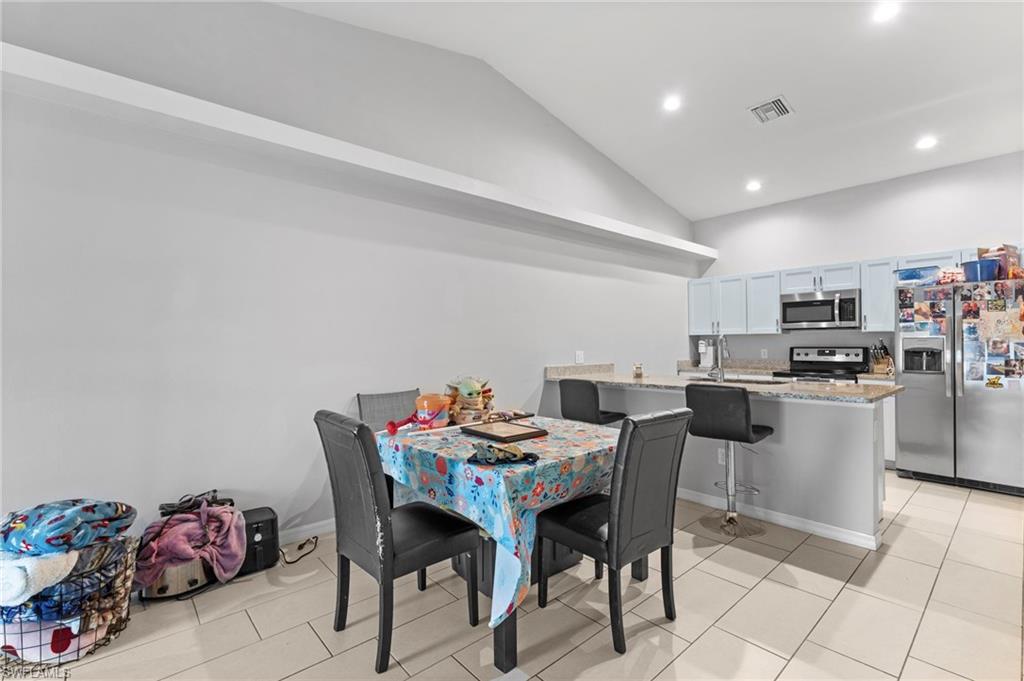 Dining room with lofted ceiling, recessed lighting, and light tile patterned flooring
