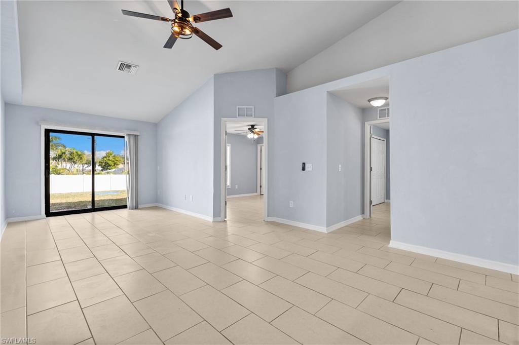 Spare room with lofted ceiling, a ceiling fan, and light tile patterned flooring