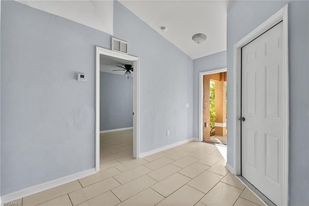 Unfurnished room featuring lofted ceiling, ceiling fan, and light tile patterned flooring
