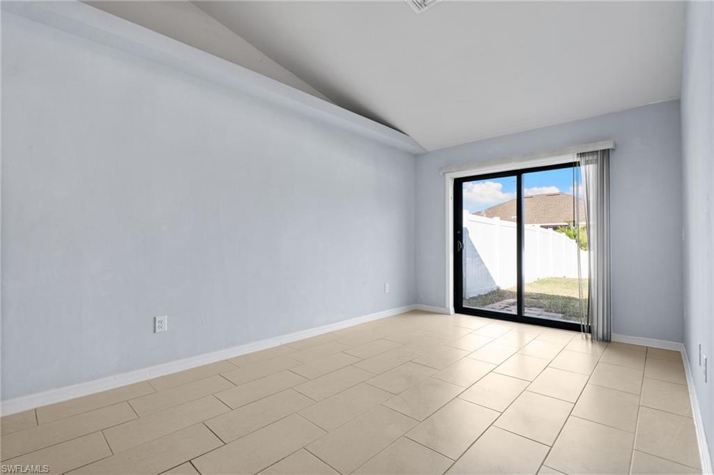 Empty room with vaulted ceiling and light tile patterned flooring