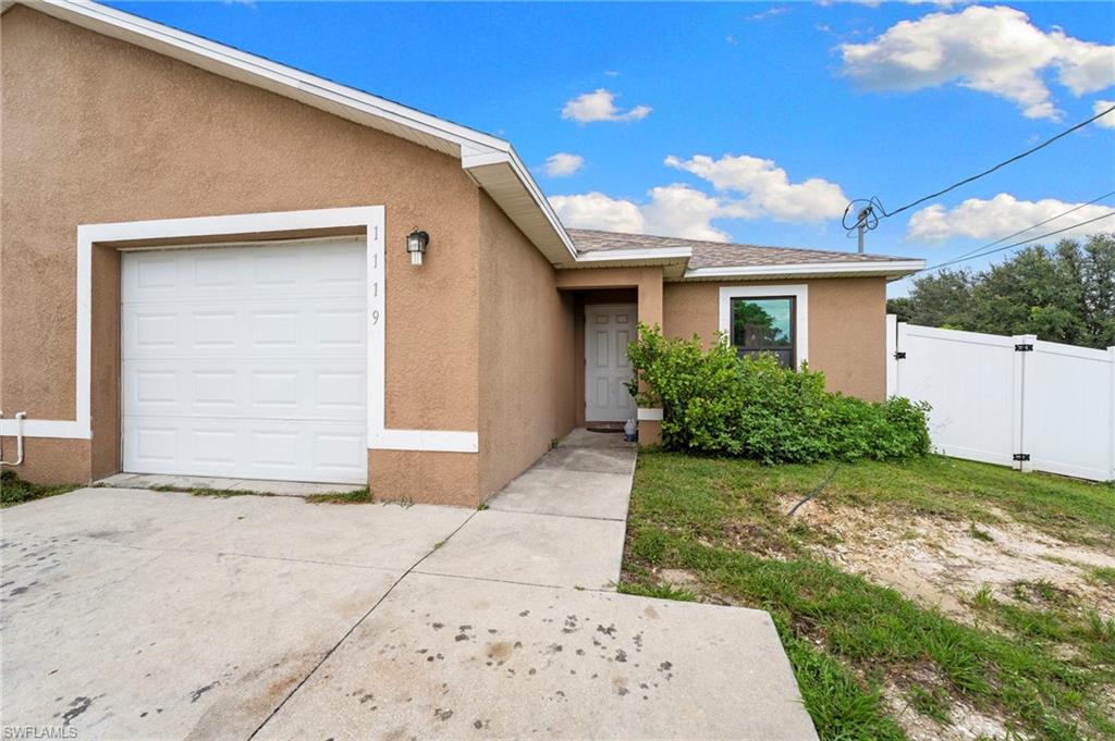 Entrance to property featuring stucco siding, a gate, and a garage