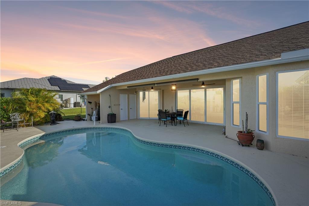 Pool at dusk with a patio area, an outdoor pool, and outdoor dining space