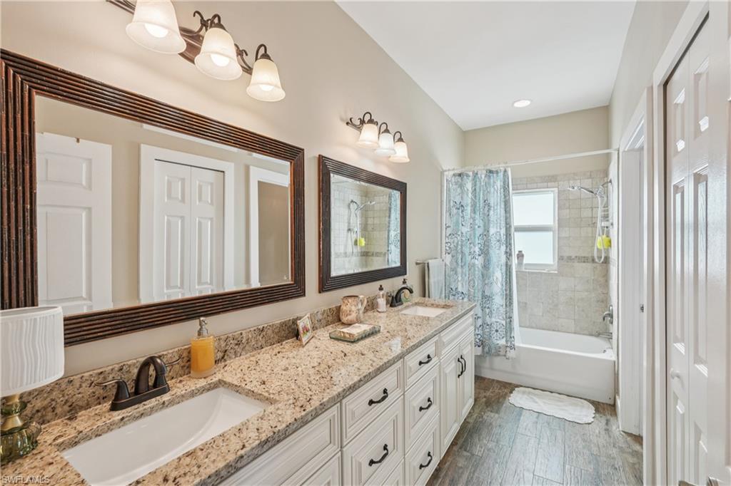 Bathroom featuring shower / bath combo, double vanity, and dark wood finished floors