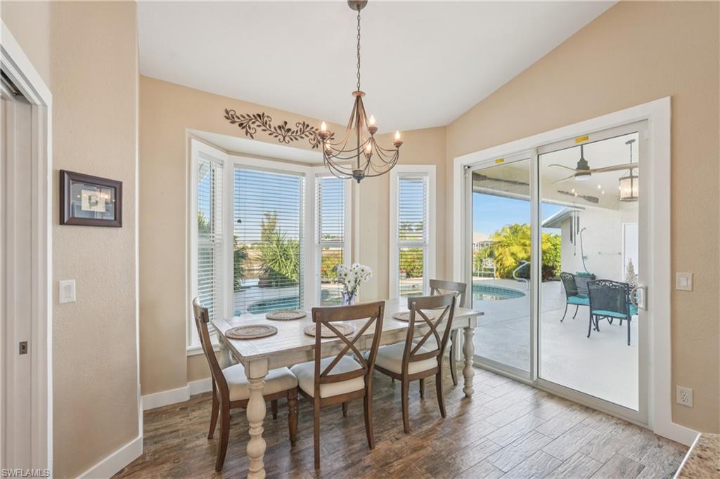 Dining area with wood finished floors, lofted ceiling, a chandelier, and ceiling fan