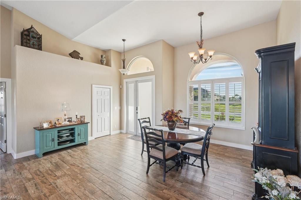 Dining room with dark wood-style flooring, a high ceiling, and a chandelier