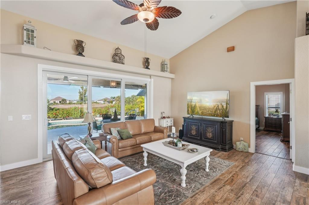 Living room with ceiling fan, hardwood / wood-style flooring, plenty of natural light, and high vaulted ceiling