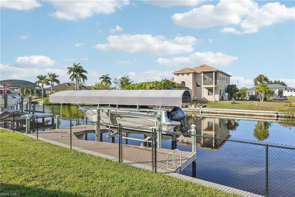 Dock with a lawn, boat lift, and a water view