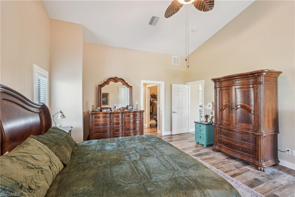 Bedroom featuring high vaulted ceiling, wood finished floors, a ceiling fan, and a walk in closet