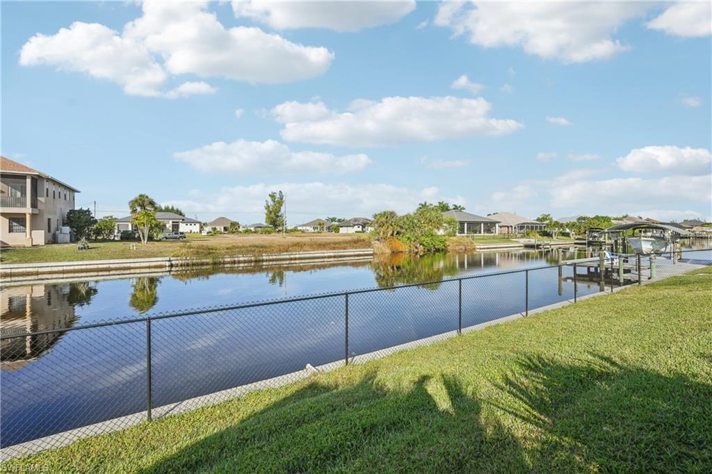 Water view featuring nearby suburban area, boat lift, and a boat dock