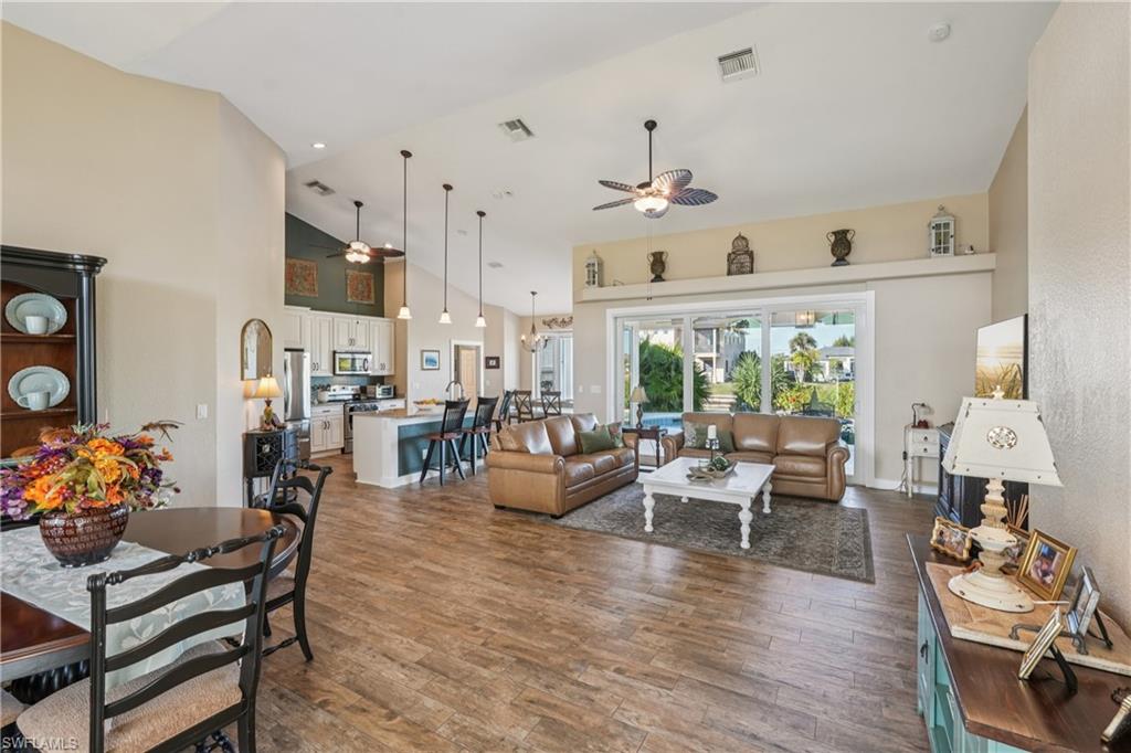 Living room with a ceiling fan, high vaulted ceiling, dark wood finished floors, and recessed lighting