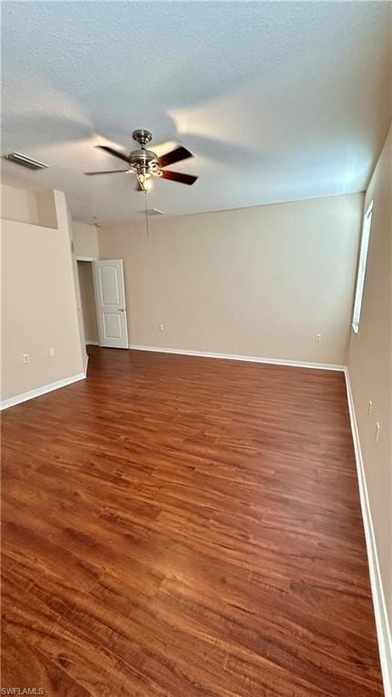 Spare room with dark wood-type flooring, a ceiling fan, and a textured ceiling