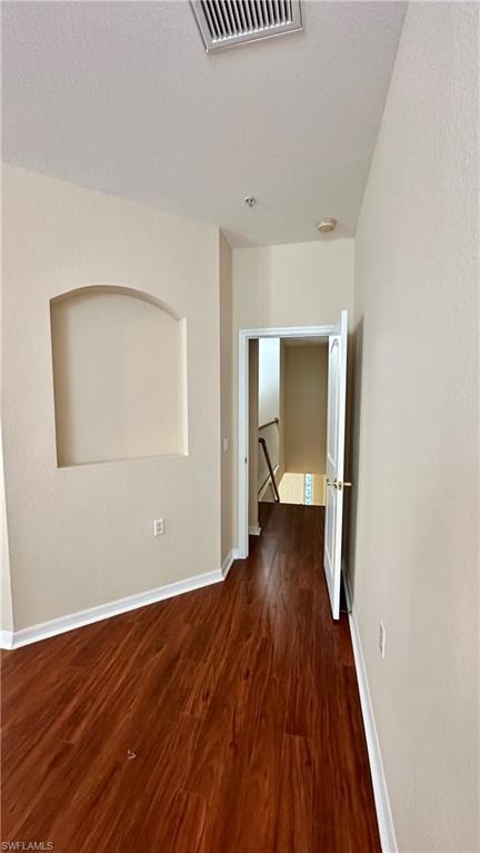 Spare room with dark wood-style floors and baseboards
