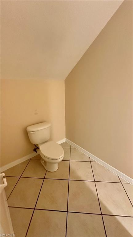 Half bath featuring lofted ceiling and light tile patterned floors