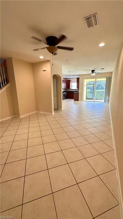 Unfurnished room with arched walkways, light tile patterned floors, recessed lighting, and a ceiling fan