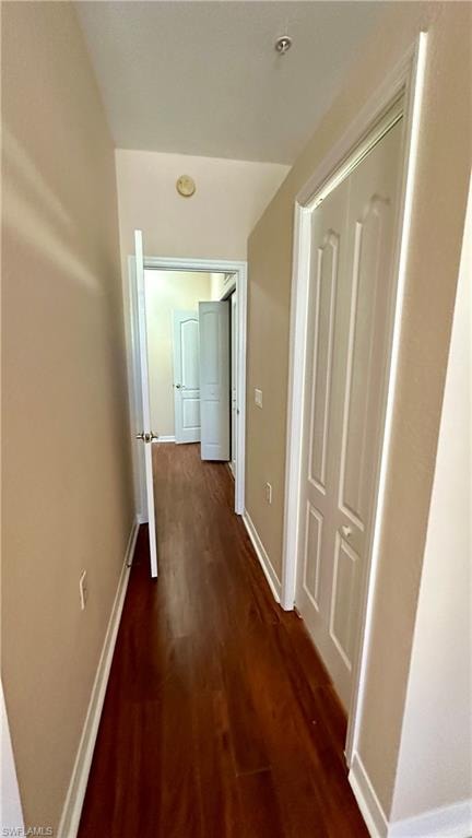 Hall with dark wood-style flooring and baseboards