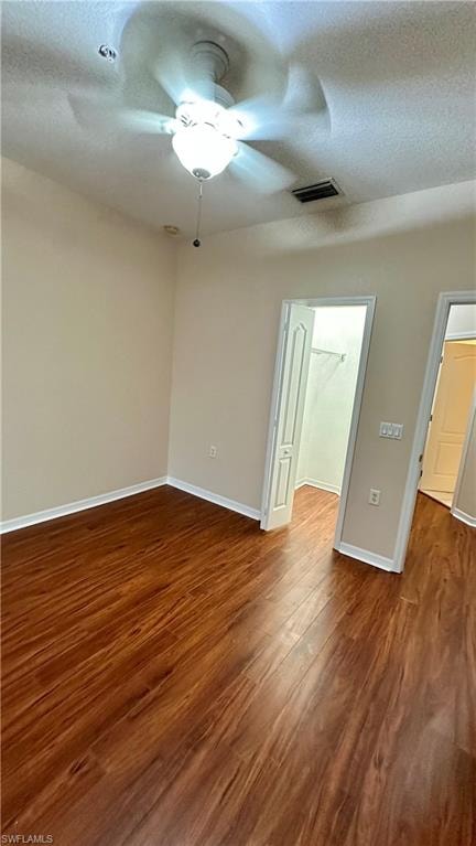 Spare room with a textured ceiling, dark wood-style floors, and a ceiling fan