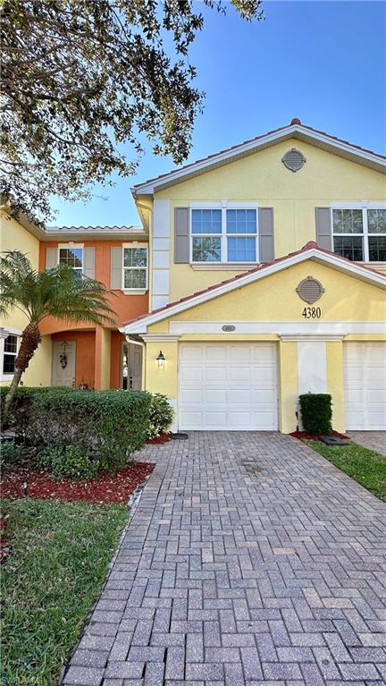 View of front facade featuring stucco siding, decorative driveway, and an attached garage