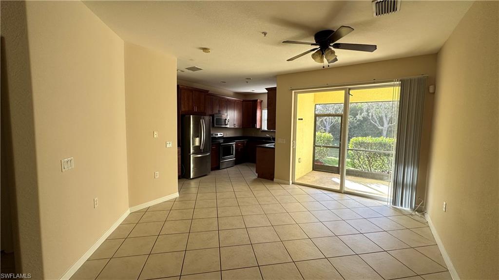 Kitchen featuring stainless steel appliances, dark countertops, dark brown cabinetry, a ceiling fan, and light tile patterned flooring
