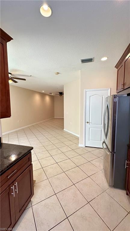 Kitchen featuring freestanding refrigerator, dark stone countertops, recessed lighting, light tile patterned flooring, and ceiling fan